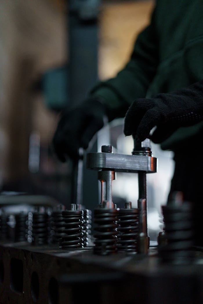 services-01 Mechanic adjusting valve springs in dimly lit workshop setting.